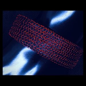 Red caged wire over black vegan leather bracelet.